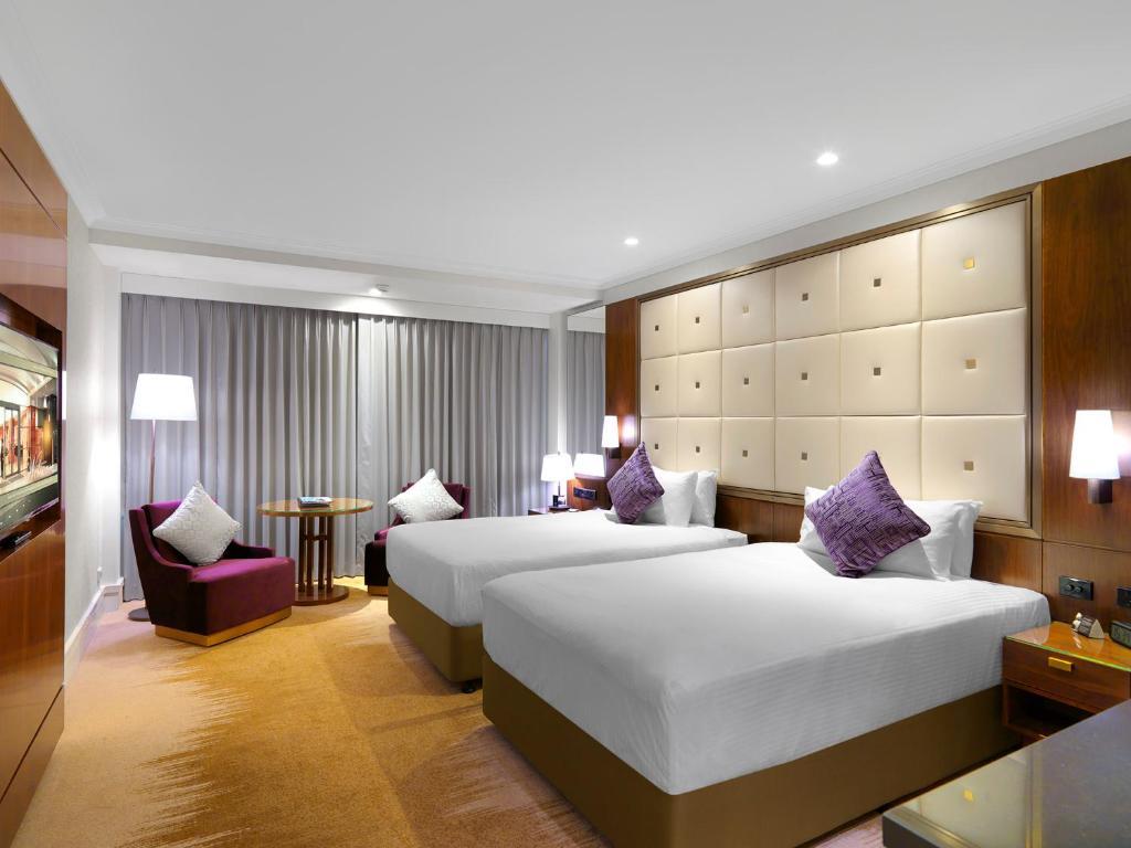 Amora Hotel Jamison Sydney Kültér fotó The photo shows a modern hotel room featuring two beds with white sheets and purple accent pillows. There is a stylish headboard behind the beds, and the room is well-lit with lamps on bedside tables. A seating area includes a purple chair and a smal