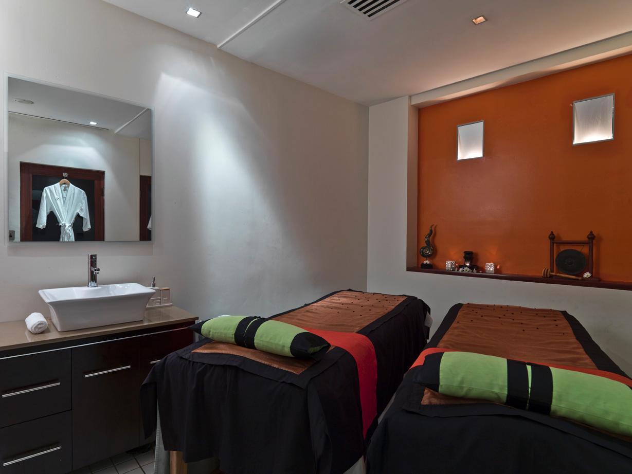 Amora Hotel Jamison Sydney Kültér fotó The photo shows a serene spa treatment room with two massage tables set up side by side. Each table is covered with dark fabric and features neatly rolled towels at the foot—one towel is green and the other is black. There is a modern sink with a min