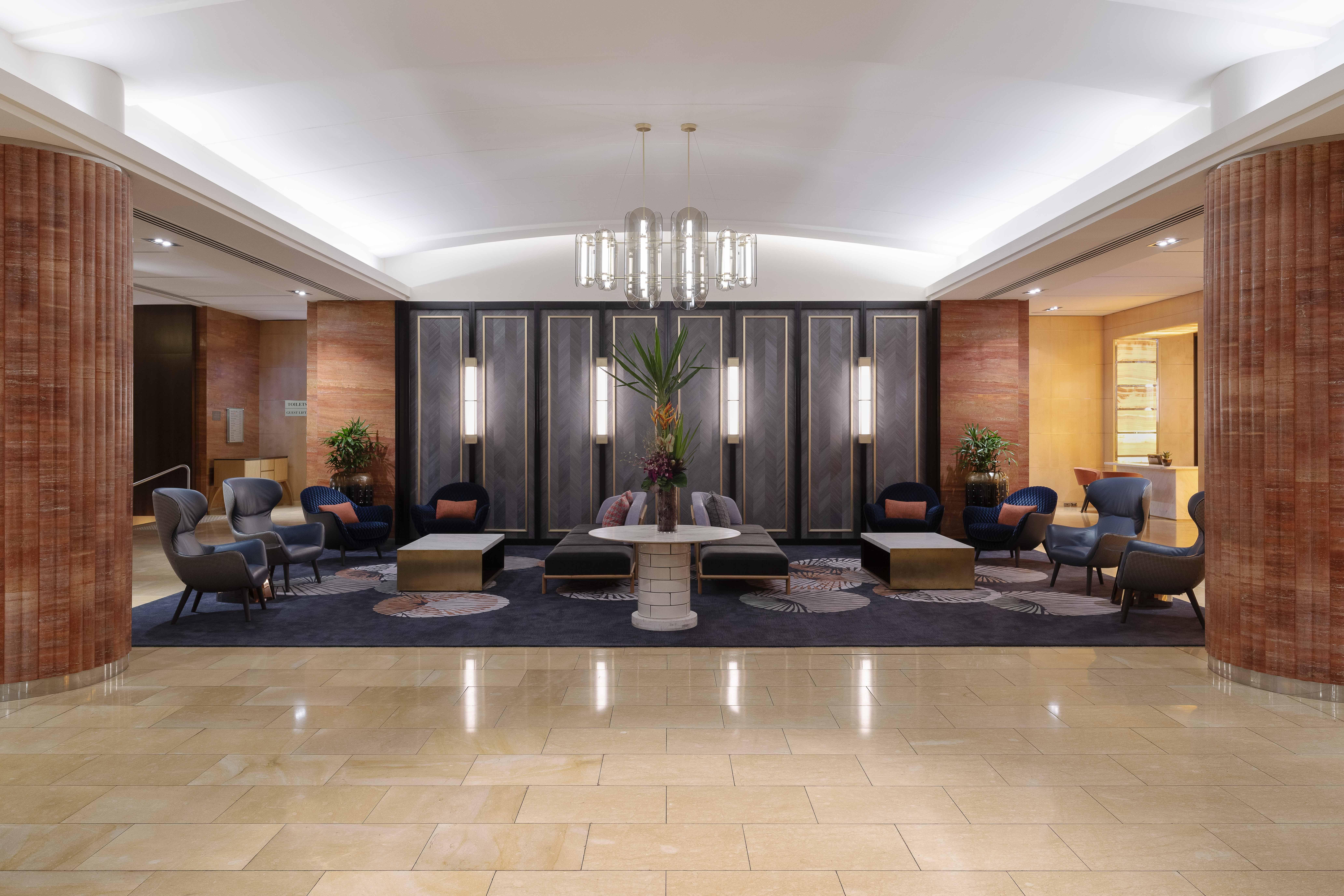 Amora Hotel Jamison Sydney Kültér fotó The photo depicts a modern hotel lobby featuring a sophisticated and welcoming ambiance. The space includes various seating arrangements with a mix of chairs and couches, positioned around a central coffee table. The decor is elegant, with a combinat