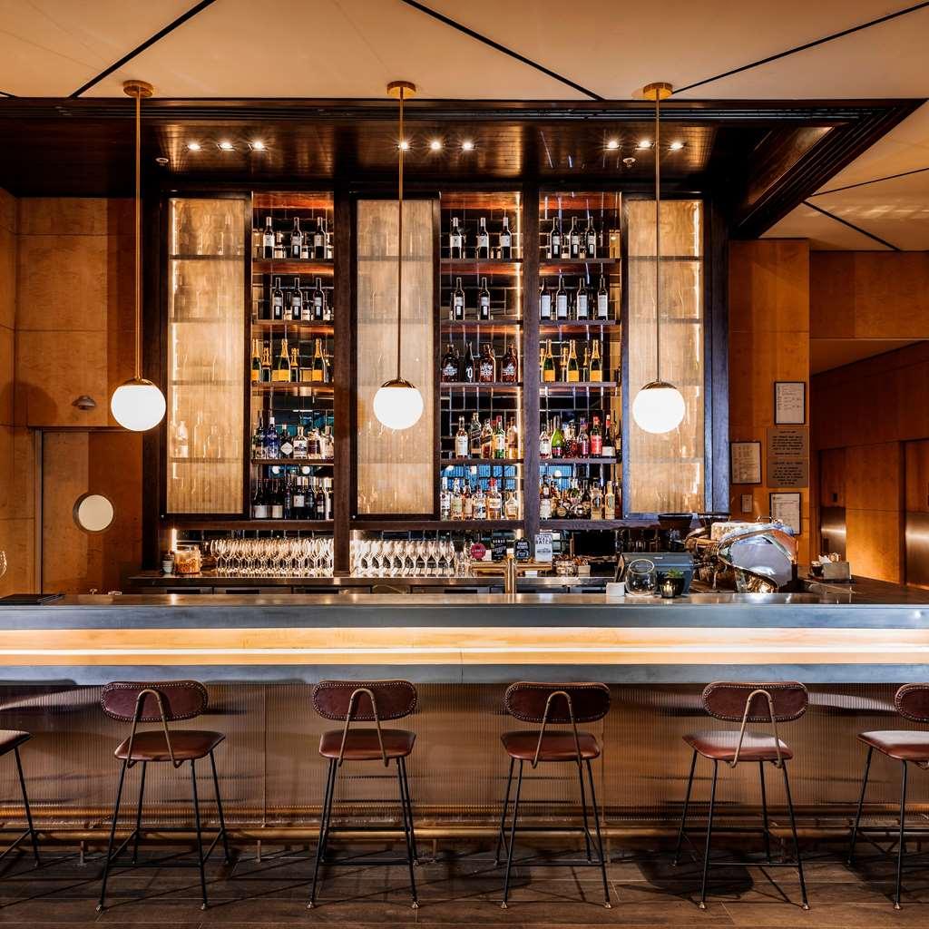 Amora Hotel Jamison Sydney Étterem fotó The photo shows a well-designed bar area. The bar has an elegant, modern aesthetic with a long, polished countertop and several backlit pendant lights hanging above. Behind the bar, there are shelves filled with various bottles of liquor, displayed n