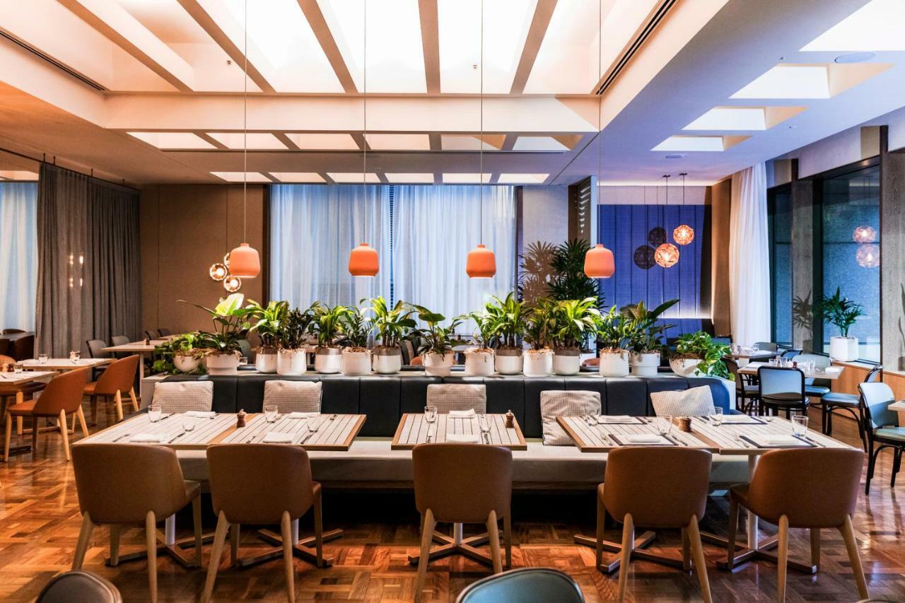 Amora Hotel Jamison Sydney Kültér fotó The photo shows the interior of a modern restaurant. It features a spacious dining area with a variety of seating options, including wooden chairs and benches. The tables are set with simple tableware, creating an inviting atmosphere. 

The decor inc